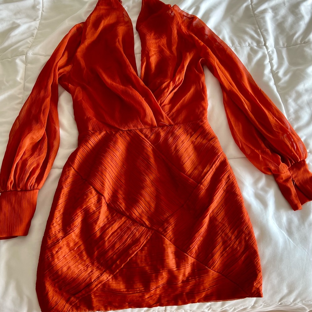 Orange mini dress with long, sheer sleeves, and plunge neckline